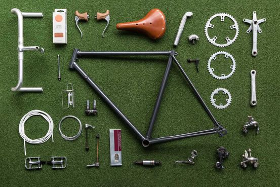 Vintage bicycle frame and parts laid out on a green mat ready for assembly